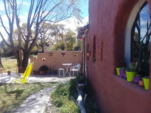 a red house with a patio and a table and chairs at Cabaña El Cardón,casita en el campo quebradeño in Humahuaca