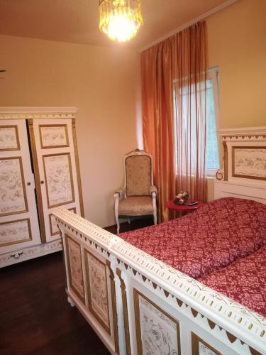 a bedroom with a large bed and a chair at Vila Kraljica in Vrdnik