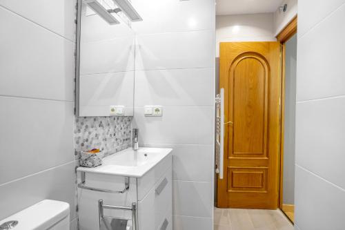 W białej łazience znajduje się umywalka i lustro. w obiekcie Apartamento Candela w Salamance