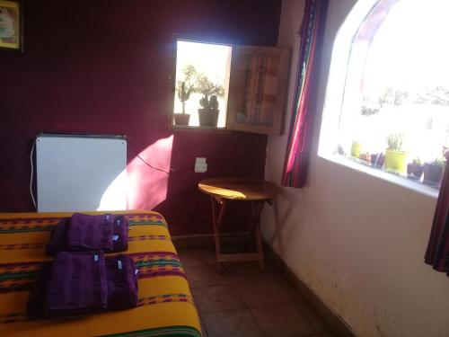 a room with a bed and a table and a window at Cabaña El Cardón,casita en el campo quebradeño in Humahuaca