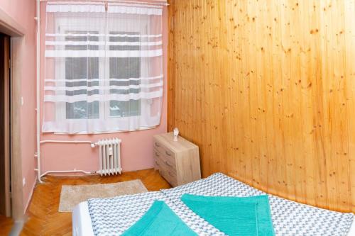 Schlafzimmer mit einem Bett und einem Fenster in der Unterkunft Kőrösi Apartman in Pécs