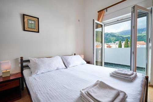 a bedroom with a white bed with a large window at Family Apartments Mont Budva in Budva