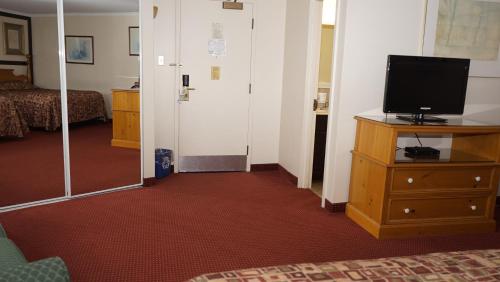 a hotel room with a television on a dresser and a bedroom at McIntosh Country Inn & Conference Centre in Morrisburg