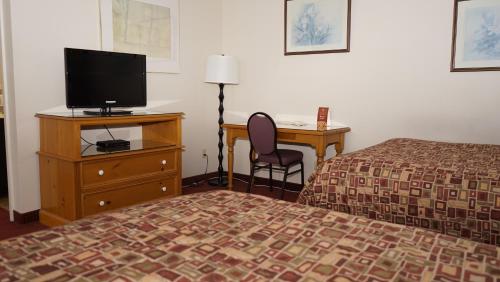 a hotel room with a bed and a desk with a television at McIntosh Country Inn & Conference Centre in Morrisburg