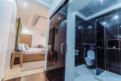 a bathroom with a shower and a bedroom at Tranquil Mews Hotel in Abuja