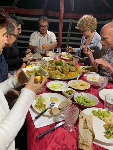 a group of people sitting at a table eating food at Khan Alsira - חאן אלסרה in Alsira
