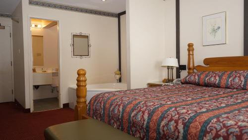 a hotel room with a bed and a bath tub at McIntosh Country Inn & Conference Centre in Morrisburg