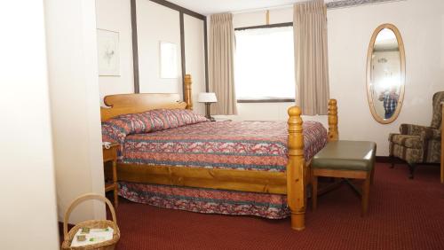 1 dormitorio con cama, espejo y silla en McIntosh Country Inn & Conference Centre, en Morrisburg