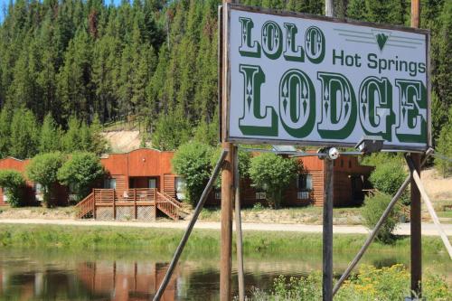 a sign for a hot springs lodge next to a lake at The Lodge at Lolo Hot Springs in Lolo