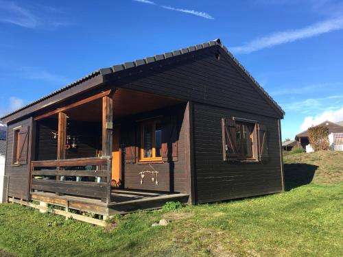 a small black house on a grass field at Chalet cosy Ignaux - Ax les thermes in Ignaux