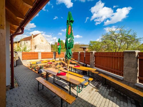 a group of picnic tables with a green umbrella at Penzion Pastouška s pohostinstvím in Moravský Krumlov