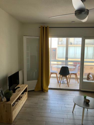 - un salon avec une grande porte coulissante en verre et une table dans l'établissement Studio l'Eldorado, à Palavas-les-Flots