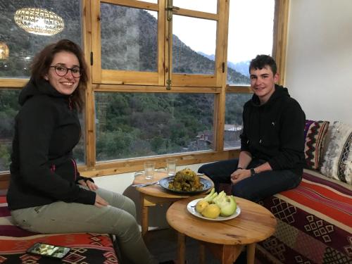 a man and woman sitting in a living room with a plate of food at Amlougui House in Marrakech