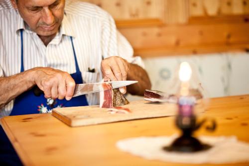 a man cutting a piece of cake on top of a table at Hotel Zum Löwen - Al Leone in Meltina
