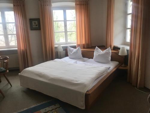 um quarto com uma grande cama branca e 2 janelas em il castello em Haiming