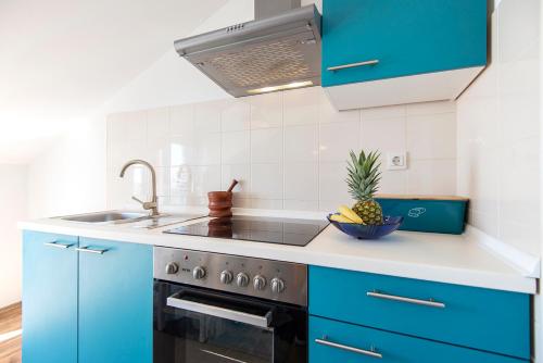 a kitchen with blue cabinets and a sink and a bowl of pineapple at Apartments CAPE Deluxe in Rtina