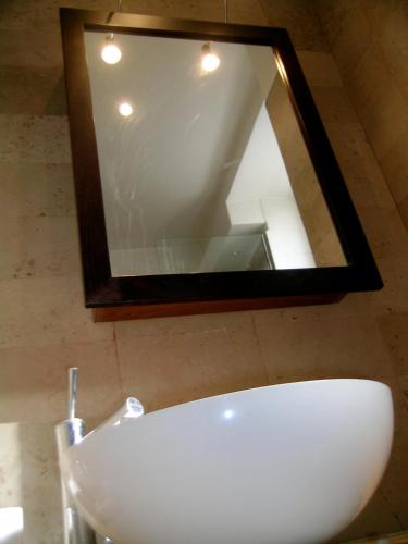 La salle de bains est pourvue d'un miroir au-dessus d'un lavabo blanc. dans l'établissement LE MARAIS 3 Bedrooms APT, à Paris