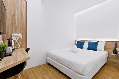 a bedroom with a white bed and a desk at Rica Hotel Usj in Subang Jaya