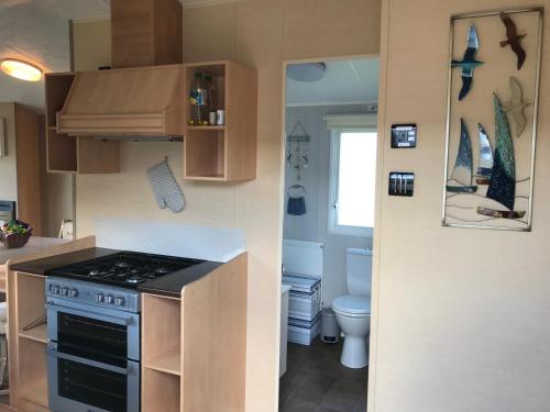 a small kitchen with a stove and a toilet at Rockley Park - Coral in Poole