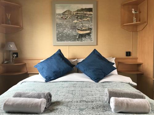 a bedroom with a bed with blue pillows at Rockley Park - Coral in Poole