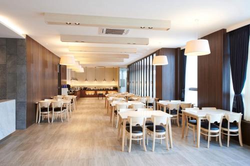 une salle à manger avec des tables et des chaises blanches dans l'établissement Hotel Mfelice, à Séoul