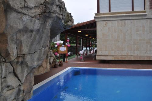 a swimming pool next to a building with a rock wall at Gran Hotel Liber & Spa Playa Golf in Noja