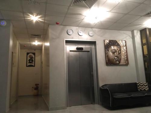 a lobby with a black couch and clocks on the wall at Hotel Les Fleurettes in Ouagadougou