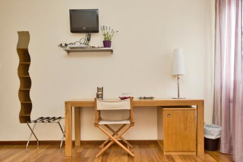 a desk with a chair and a television on a wall at Oasi Hotel in Levanto