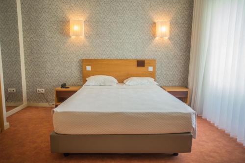 a bedroom with a bed and two lights on the wall at Hotel Brazão in Vila do Conde
