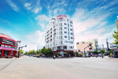 a white building with a red sign on top of it at Hoang Long Hotel Phan Thiết in Phan Thiet