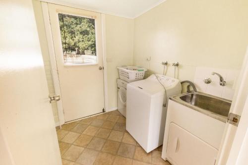 a small kitchen with a sink and a washing machine at Lakescapes Cottage in Metung