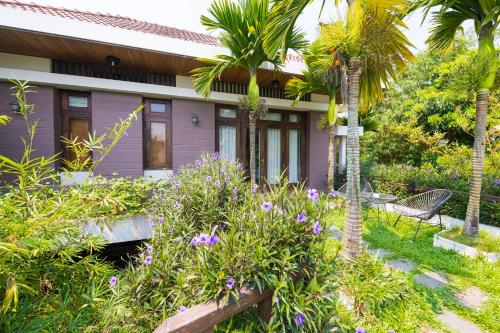 a house with palm trees and flowers in front of it at Hanging Garden Hoi An in Hoi An