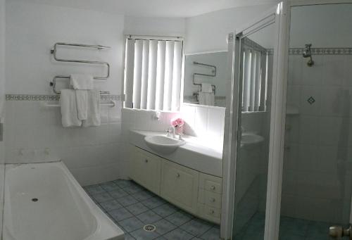 La salle de bains est pourvue d'un lavabo, d'une baignoire et d'une douche. dans l'établissement Corlette Retreat, à Corlette