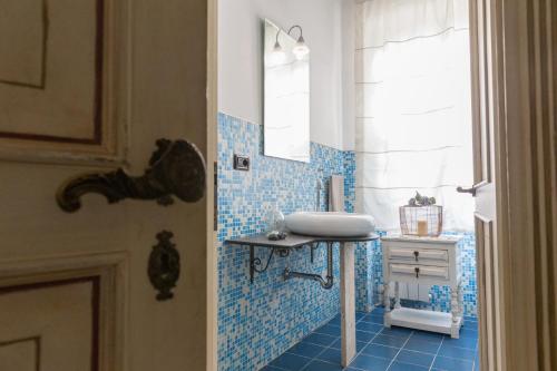 a blue tiled bathroom with a sink and a mirror at filobrocante in Torre Santa Susanna