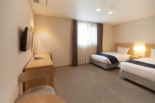 a hotel room with two beds and a television at Towerhill Hotel in Busan