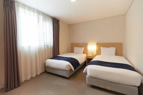 a hotel room with two beds and a window at Towerhill Hotel in Busan