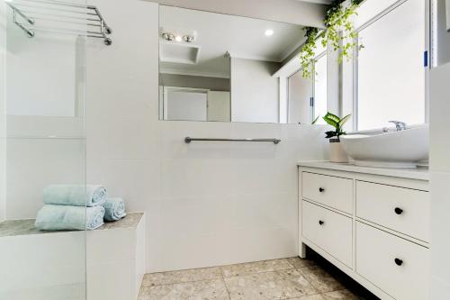 a white bathroom with a sink and a shower at 'In The Vines' Guest Cottage, Barossa Valley in Lights Pass