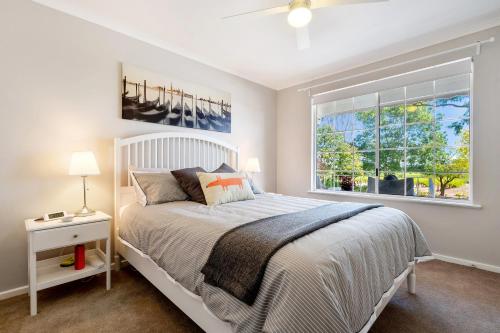 1 dormitorio con cama blanca y ventana en 'In The Vines' Guest Cottage, Barossa Valley en Lights Pass