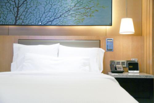 a bed in a hotel room with a phone next to it at The Westin Qingdao - Instagrammable in Qingdao