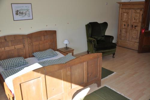 a bedroom with a wooden bed and a green chair at Gasthof Kronreith in Maria Alm am Steinernen Meer