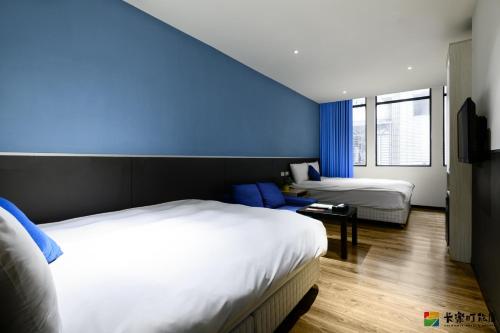 een slaapkamer met 2 bedden en een blauwe muur bij ColorMix Hotel & Hostel in Taipei