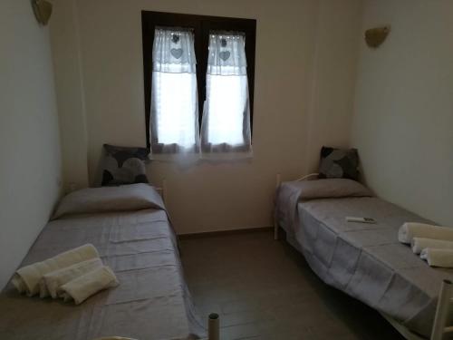 two beds in a room with a window at B&B Nino in Olbia