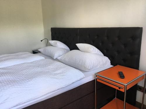a bed with white pillows and a side table at Eifel-Quartiere "Pension Müscher Bahnhof" in Müsch