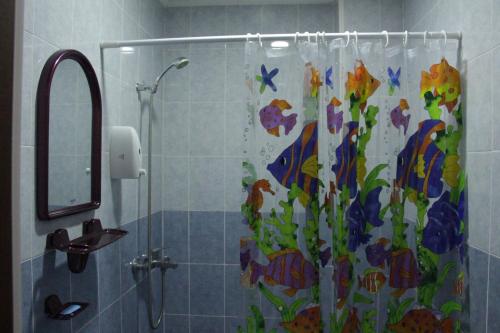 La salle de bains est pourvue d'une douche avec rideau de douche et de fleurs. dans l'établissement Snow Leopard Hostel, à Karakol