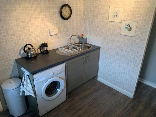 a laundry room with a sink and a washing machine at Heatherland Cottage in Portree
