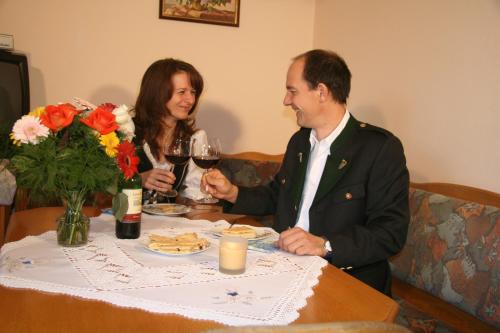 a man and woman sitting at a table with a glass of wine at Bio-Bauernhof Wilfling in Miesenbach