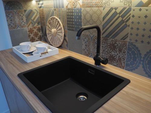 a black kitchen sink with two cups on a counter at Suite Parolin in Marostica