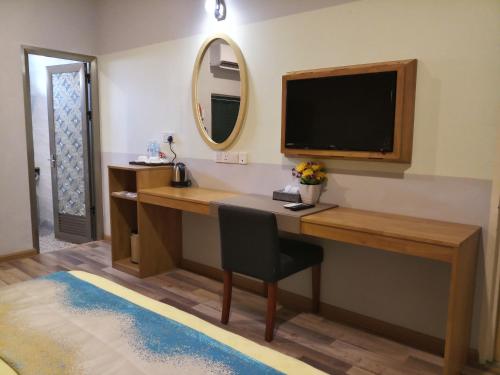 um quarto com uma secretária, uma televisão e um espelho em K GARDEN HOTEL (IPOH) SDN BHD em Ipoh