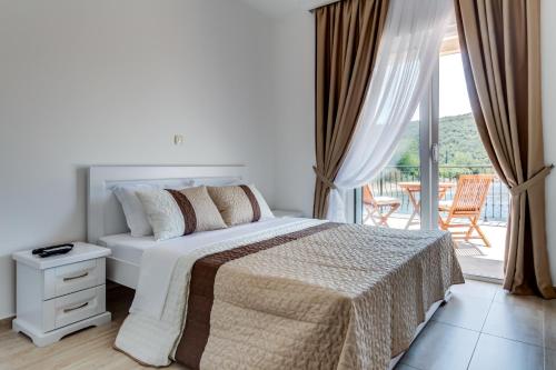 a white bedroom with a bed and a balcony at Villa SAN Apartments in Tivat