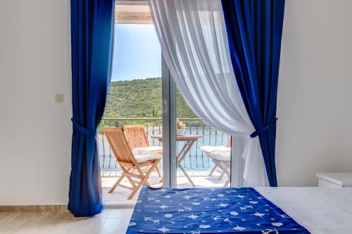 una camera da letto con tende blu e un balcone con tavolo di Villa SAN Apartments a Tivat